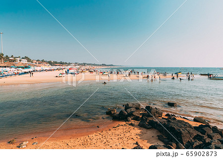 Mapusa, Anjuna, Goa, India. People Visit And Relax On Baga Beach At Sunny Evening Under Blue Sky. Mapusa, Anjuna, Goa, India. People Visit And Relax On Baga Beach At Sunny Evening Under Blue Sky. 65902873