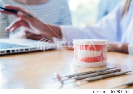 Dentist showing and explaining teeth disease treatment to patient using teeth model denture. Dentist showing and explaining teeth disease treatment to patient using teeth model denture. 65903450