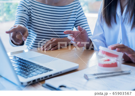 Dentist showing and explaining teeth disease treatment to patient using teeth model denture. Dentist showing and explaining teeth disease treatment to patient using teeth model denture. 65903567