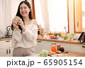 Cute asian woman eating sandwich and prepare to make breakfast in the kitchen. 65905154