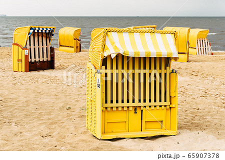 Sandy beach and typical hooded beach chairs in Cuxhaven in the North Sea coast Sandy beach and typical hooded beach chairs in Cuxhaven in the North Sea coast 65907378