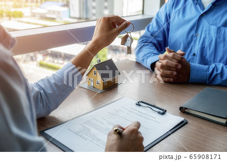 Estate agent holding a key and asking costumer for contract to buy, get insurance or loan estate. 65908171