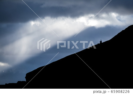 High slope hill with lighthouse under the clouds 65908226