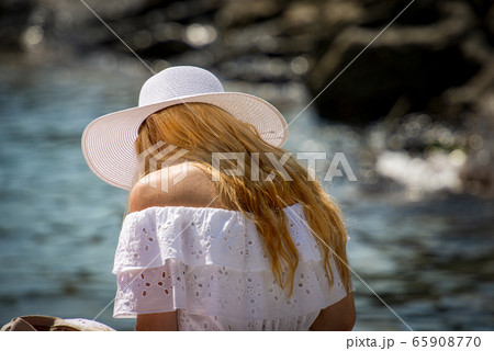 Young blonde woman with white sun hat on the beach 65908770