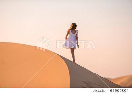 Girl among dunes in desert in United Arab Emirates Girl among dunes in desert in United Arab Emirates 65909304
