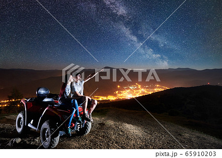Couple tourists with atv quad bike under night starry sky Couple tourists with atv quad bike under night starry sky 65910203
