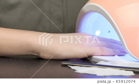 Gel Polish at home. Hand in a glowing UV lamp. 65912074