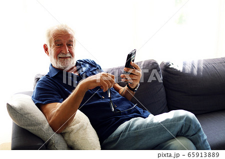 Elderly senior man sitting alone and playing mobile phone at home. Elderly senior man sitting alone and playing mobile phone at home. 65913889
