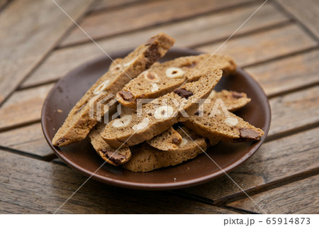 Homemade Biscotti with nuts and dark chocolate on a brown plate on a wooden table 65914873
