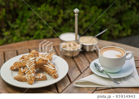 a plate of homemade biscotti cookies and a Cup of coffee with cream and sugar on the wooden table. Blurred background 65914943