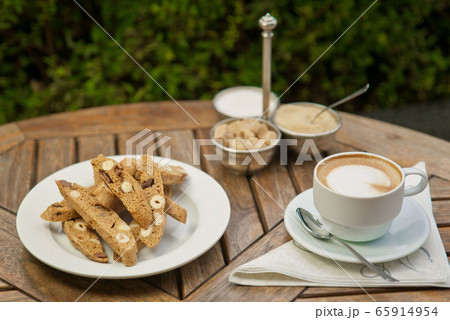 a plate of homemade biscotti cookies and a Cup of coffee with cream and sugar on the wooden table. Blurred background 65914954