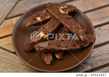 homemade chocolate biscotti with nuts and raisins on a brown plate on a wooden table homemade chocolate biscotti with nuts and raisins on a brown plate on a wooden table 65914957