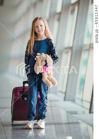 Adorable little girl in airport with her luggage waiting for boarding Adorable little girl in airport with her luggage waiting for boarding 65915347