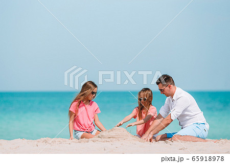 Father and kids making sand castle at tropical beach. Family playing with beach toys 65918978