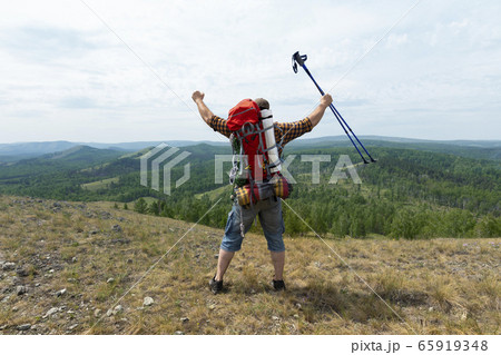 Middle aged hiker backpacker man growing hands with trekking poles during high altitude acclimatization walk. Middle aged hiker backpacker man growing hands with trekking poles during high altitude acclimatization walk. 65919348
