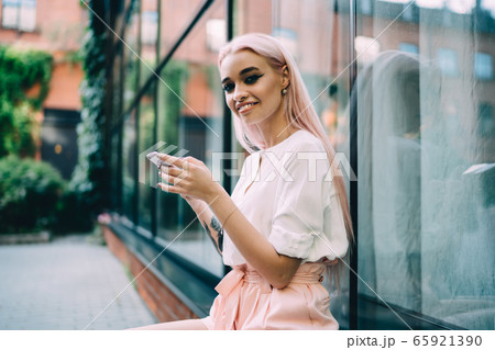 Attractive Caucasian teenager with tattooed hand pondering on information from smartphone gadget Attractive Caucasian teenager with tattooed hand pondering on information from smartphone gadget 65921390
