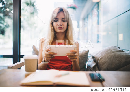 Young woman using tablet in cozy modern cafe Young woman using tablet in cozy modern cafe 65921515
