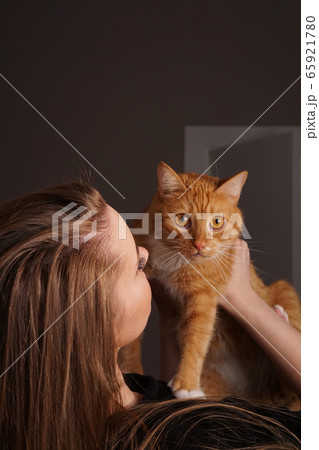 Beautiful young woman with a fluffy red cat Beautiful young woman with a fluffy red cat 65921780