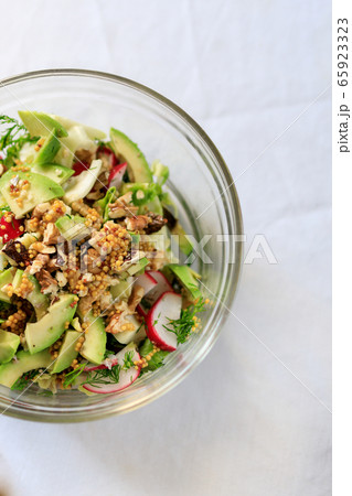 salad in a transparent bowl of avocado, walnuts, green salad, radish French mustard on a table with 65923323