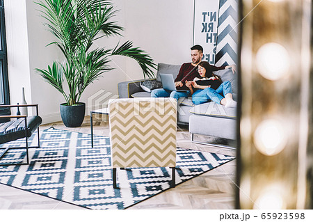 Young caucasian wife and husband watching movie togetherness relaxing on comfort sofa Young caucasian wife and husband watching movie togetherness relaxing on comfort sofa 65923598
