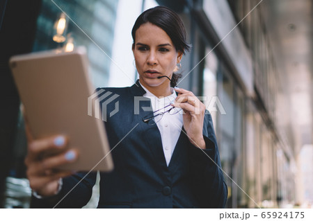 Executive lady having video call on tablet in business district Executive lady having video call on tablet in business district 65924175