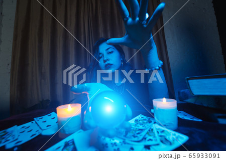 Woman fortune-teller guesses fate of night at table with candles Woman fortune-teller guesses fate of night at table with candles 65933091