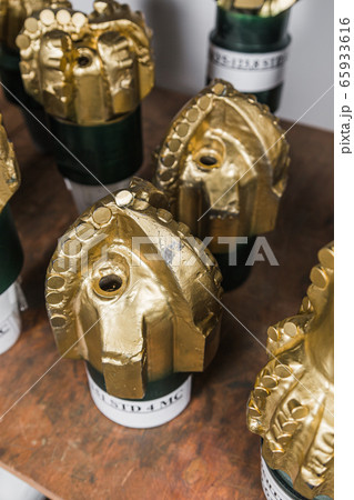 Golden color rock Drill Bits on shelving in stock. Oil drilling equipment for drilling rig operation on oil platform in oil and gas industry. Brand new PDC Polycrystalline Diamond Compact drilling bit 65933616