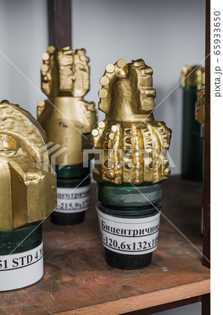Golden color rock Drill Bits on shelving in stock. Oil drilling equipment for drilling rig operation on oil platform in oil and gas industry. Brand new PDC Polycrystalline Diamond Compact drilling bit 65933650
