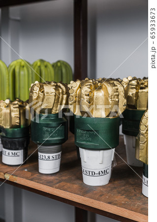Golden color rock Drill Bits on shelving in stock. Oil drilling equipment for drilling rig operation on oil platform in oil and gas industry. Brand new PDC Polycrystalline Diamond Compact drilling bit 65933673