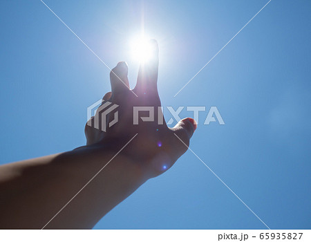 太陽に伸ばす手 光の写真素材
