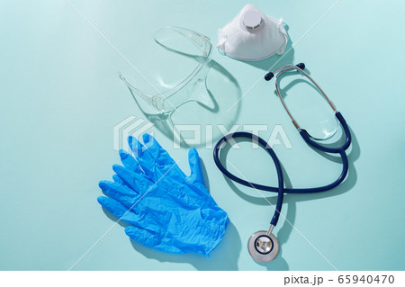 Phonendoscope, respirator, medical gloves and protective glasses on a blue background. 65940470