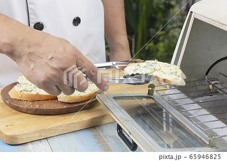 Chef put garlic bread to the oven by tongs Chef put garlic bread to the oven by tongs 65946825