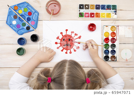 A child draws a coronovirus on a piece of paper. The drawing was made by a child using color paints. Children's drawing. View from above 65947071