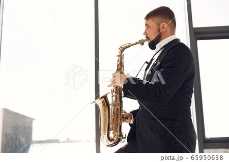 Man in black suit standing with a saxophone 65950638