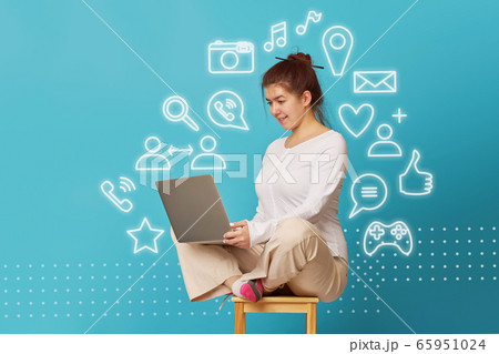 Woman is siting in lotus position on a chair with a laptop. 65951024