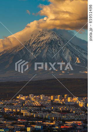 Evening view from above of Petropavlovsk-Kamchatsky City at sunset on background active volcano of Kamchatka Peninsula. Evening view from above of Petropavlovsk-Kamchatsky City at sunset on background active volcano of Kamchatka Peninsula. 65951496