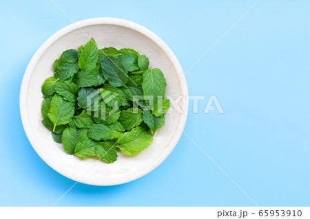 Bowl of mint leaves on blue background. 65953910