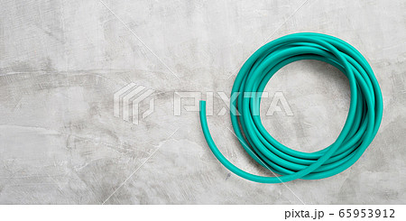 Green garden hose on concrete background. 65953912