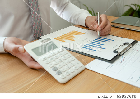 A business man is sitting at a desk and calculating financial graphs about real estate investment expenditures 65957689