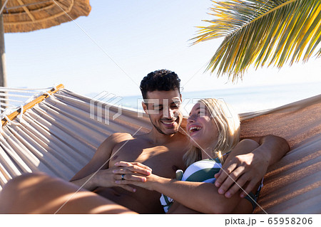 Caucasian couple lying on a hammock at the beach. 65958206