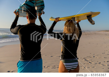 Caucasian couple holding surfboards at the beach. 65958367