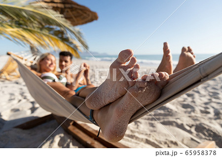 Caucasian couple lying on a hammock at the beach. Caucasian couple lying on a hammock at the beach. 65958378