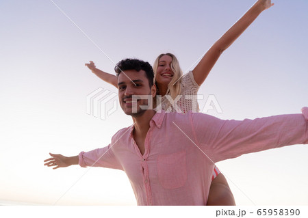 Caucasian couple enjoying time at the beach during the sunset 65958390