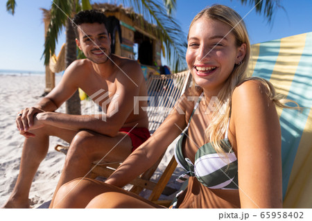 Caucasian couple sitting on deck chairs at the beach 65958402