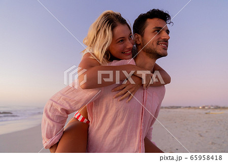 Caucasian couple enjoying time at the beach during the sunset Caucasian couple enjoying time at the beach during the sunset 65958418