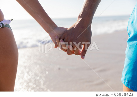 Caucasian couple standing in water at the beach. Caucasian couple standing in water at the beach. 65958422