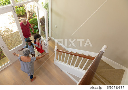 Mixed race senior man arriving home with his grandson and granddaughter Mixed race senior man arriving home with his grandson and granddaughter 65958435