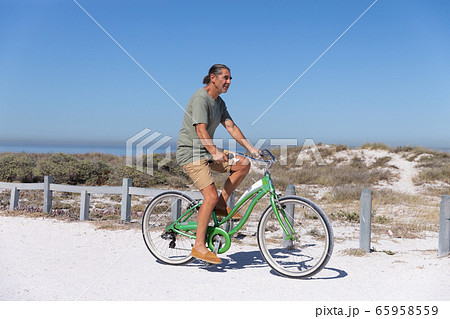 Senior Caucasian man riding a bike at the beach 65958559