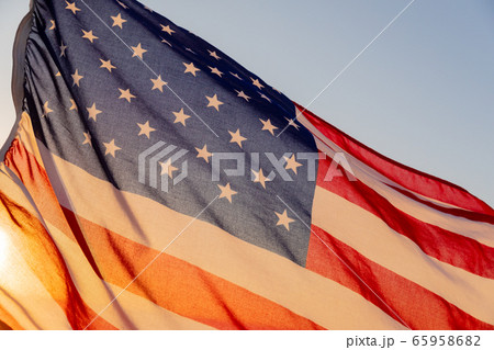The sun seen through a US flag on a beach 65958682