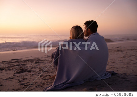 Caucasian couple enjoying time at the beach during the sunset 65958685